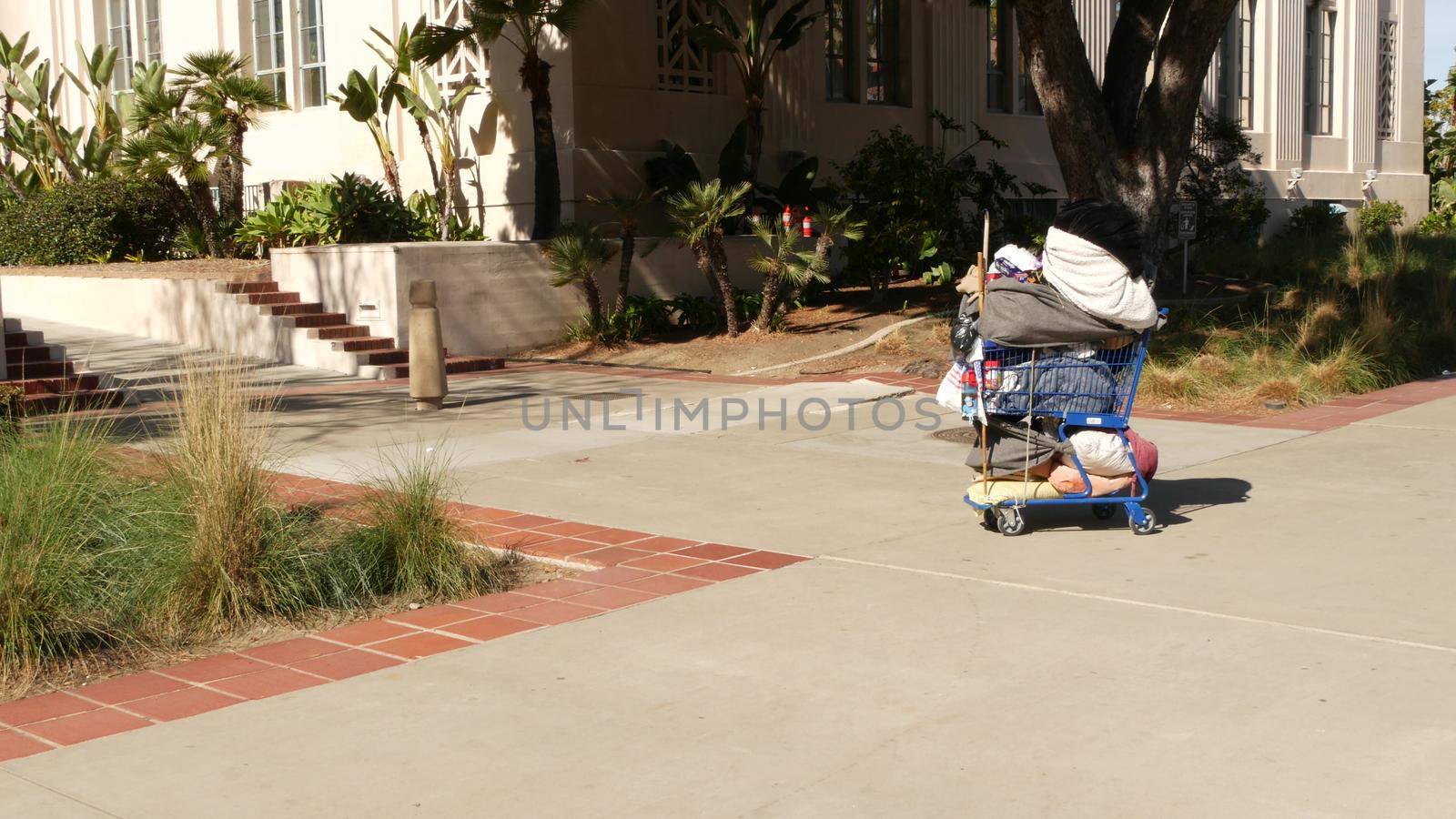 SAN DIEGO, CALIFORNIA USA - 30 JAN 2020: Stuff of homeless street people on walkway, truck on roadside. Begging problem in downtown of city near Los Angeles. Jobless beggars trolley cart on pavement by DogoraSun