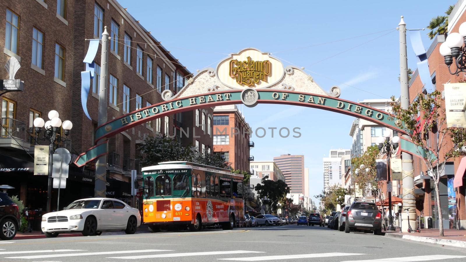 SAN DIEGO, CALIFORNIA USA - 13 FEB 2020: Gaslamp Quarter historic entrance arch sign on 5th avenue. Orange iconic retro trolley, hop-on hop-off bus and tourist landmark, Old Town Sightseeing Tour.