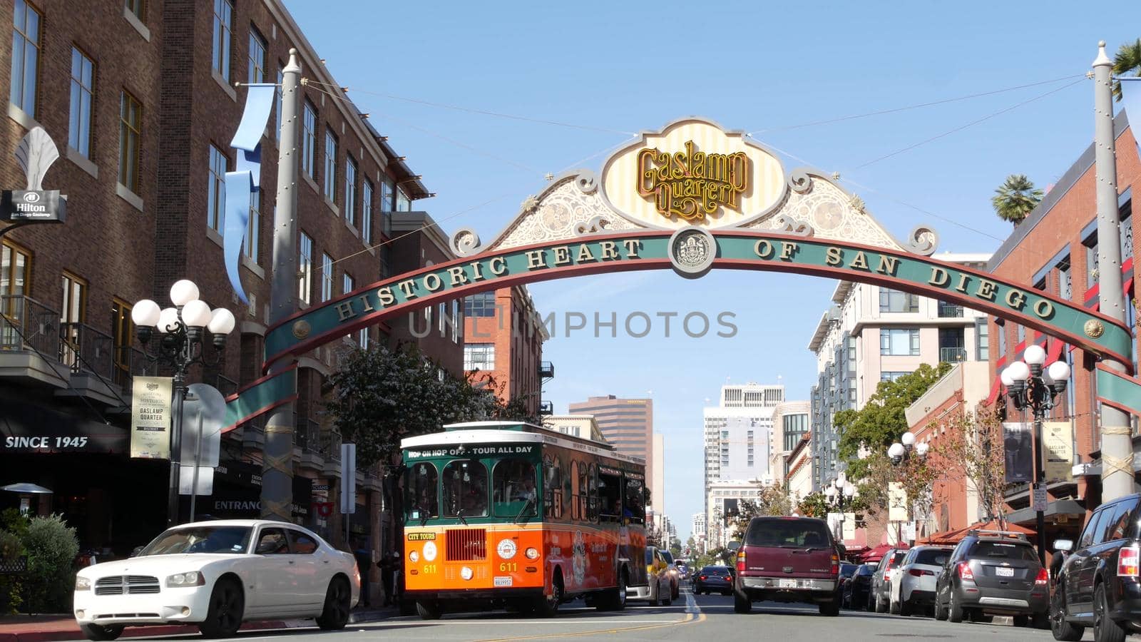 SAN DIEGO, CALIFORNIA USA - 13 FEB 2020: Gaslamp Quarter historic entrance arch sign on 5th avenue. Orange iconic retro trolley, hop-on hop-off bus and tourist landmark, Old Town Sightseeing Tour by DogoraSun