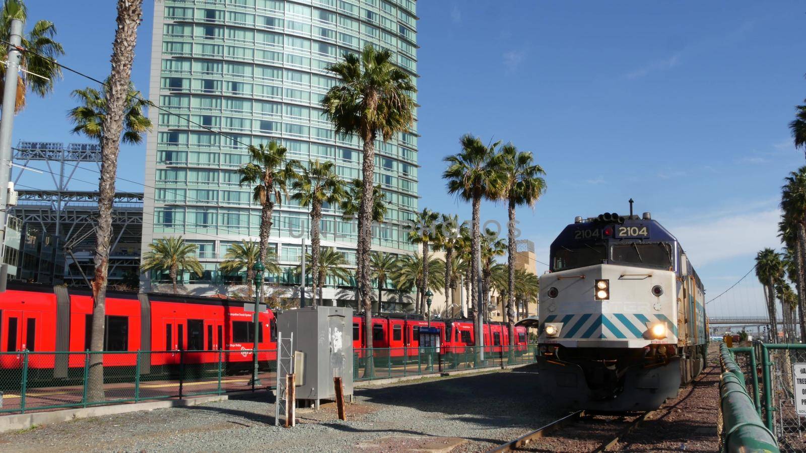 SAN DIEGO, CALIFORNIA USA - 13 FEB 2020: Coaster Commuter and red MTS trolley, public rail transportation in America. Express passenger railway train and tram, railroad NCTD transport near Santa Fe by DogoraSun