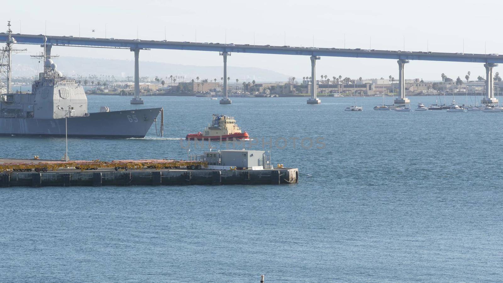 SAN DIEGO, CALIFORNIA USA - 13 FEB 2020: Tugboat pulling USS Chosin CG-65, military warship of US Navy fleet. Tug towing maritime battleship in port harbor. United States Armed Forces naval ship by DogoraSun