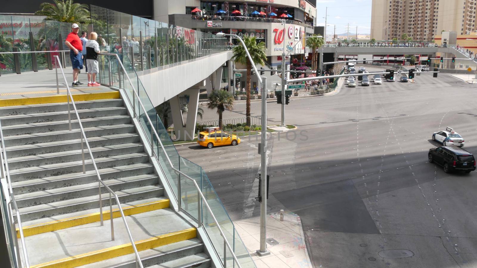 LAS VEGAS, NEVADA USA - 7 MAR 2020: The Strip boulevard with luxury casino and hotels in gambling sin city. Car traffic on road to Fremont street in tourist money playing resort. People on sky bridge by DogoraSun