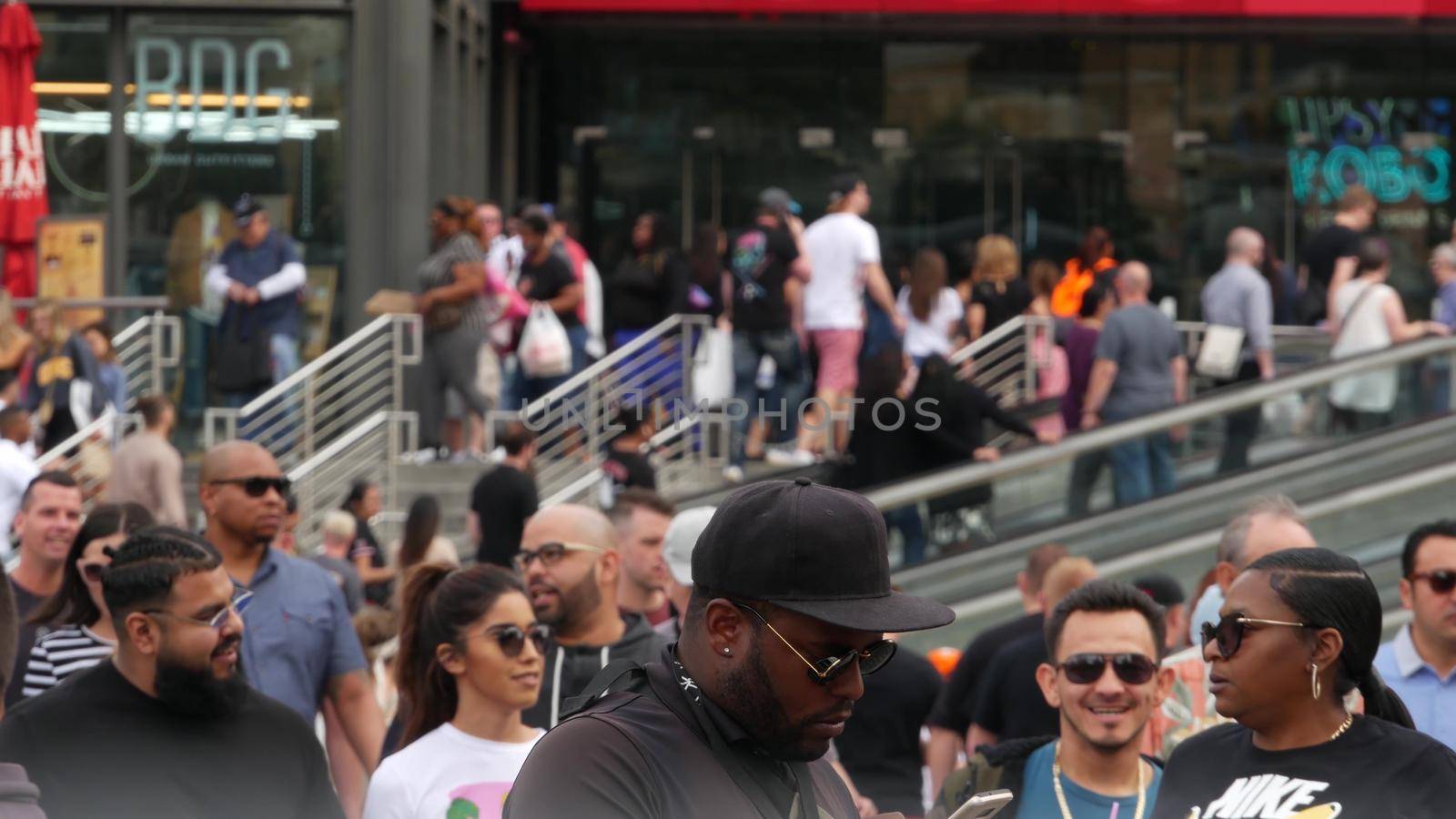 LAS VEGAS, NEVADA USA - 7 MAR 2020: People on pedestrian walkway. Multicultural men and women walking on city promenade. Crowd of citizens on sidewalk. Diversity of multiracial faces in metropolis.