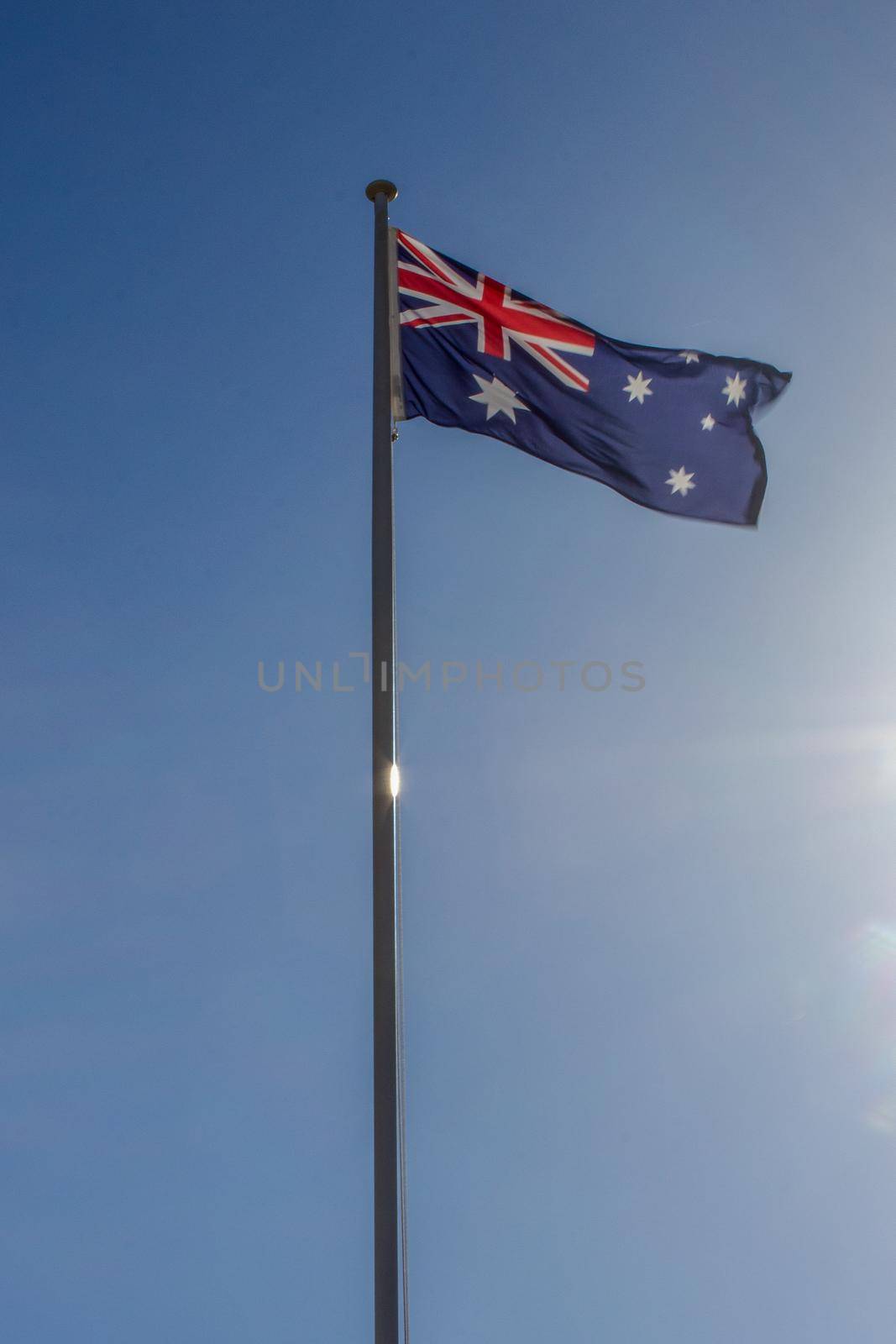 Australian flag slowly waving on the beautiful blue sky by bettercallcurry