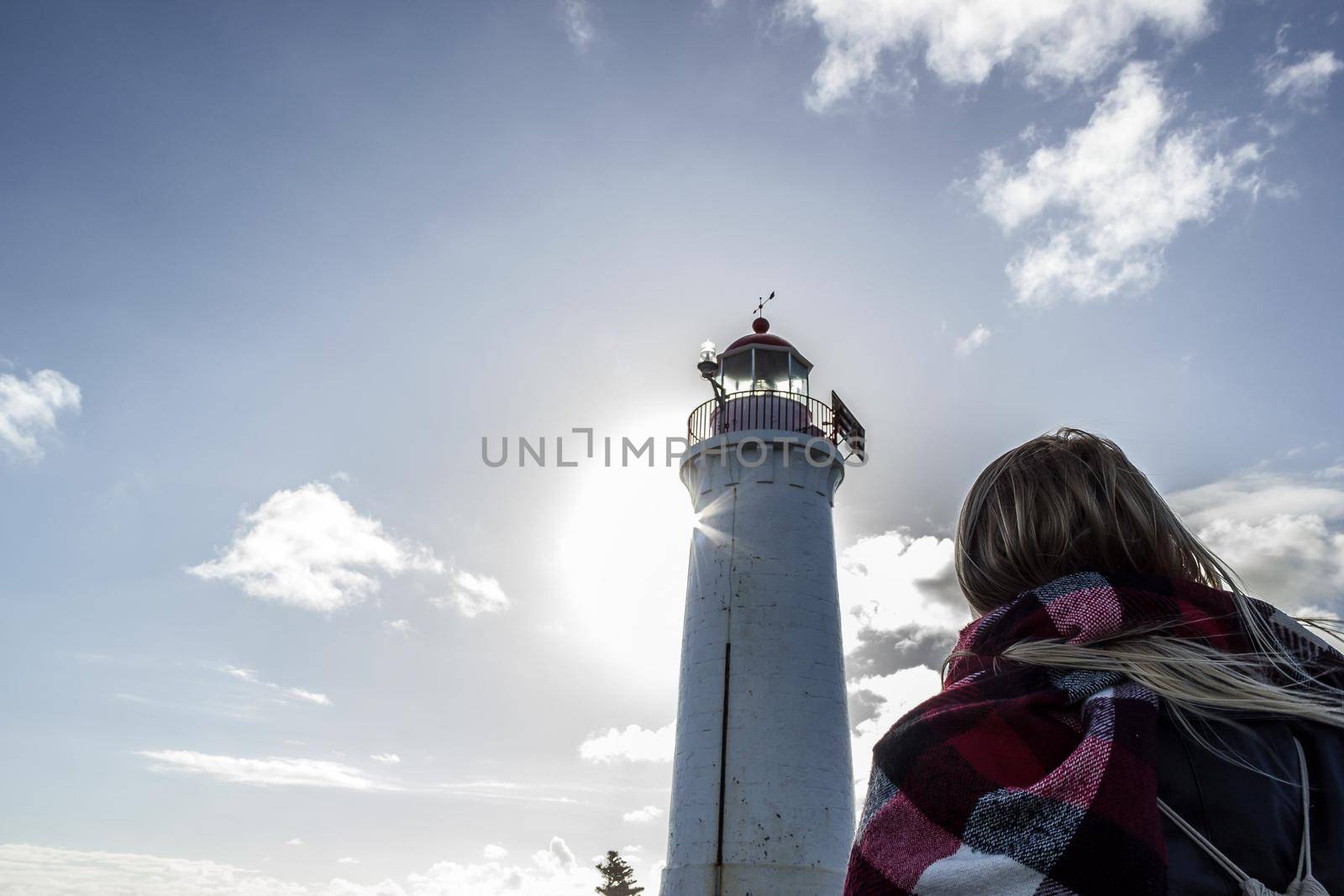 A young woman dressed in black is looking towards a white lighthouse , Great Ocean Road by bettercallcurry