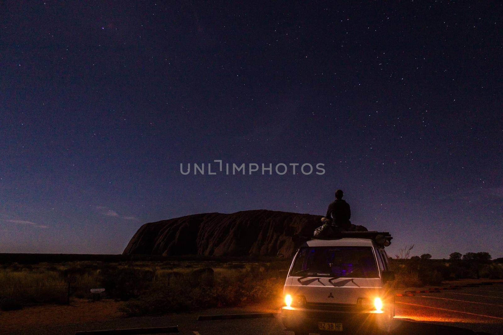 Uluru at night with car with a young man on the car, ayers Rock, the Red Center of Australia, Australia by bettercallcurry