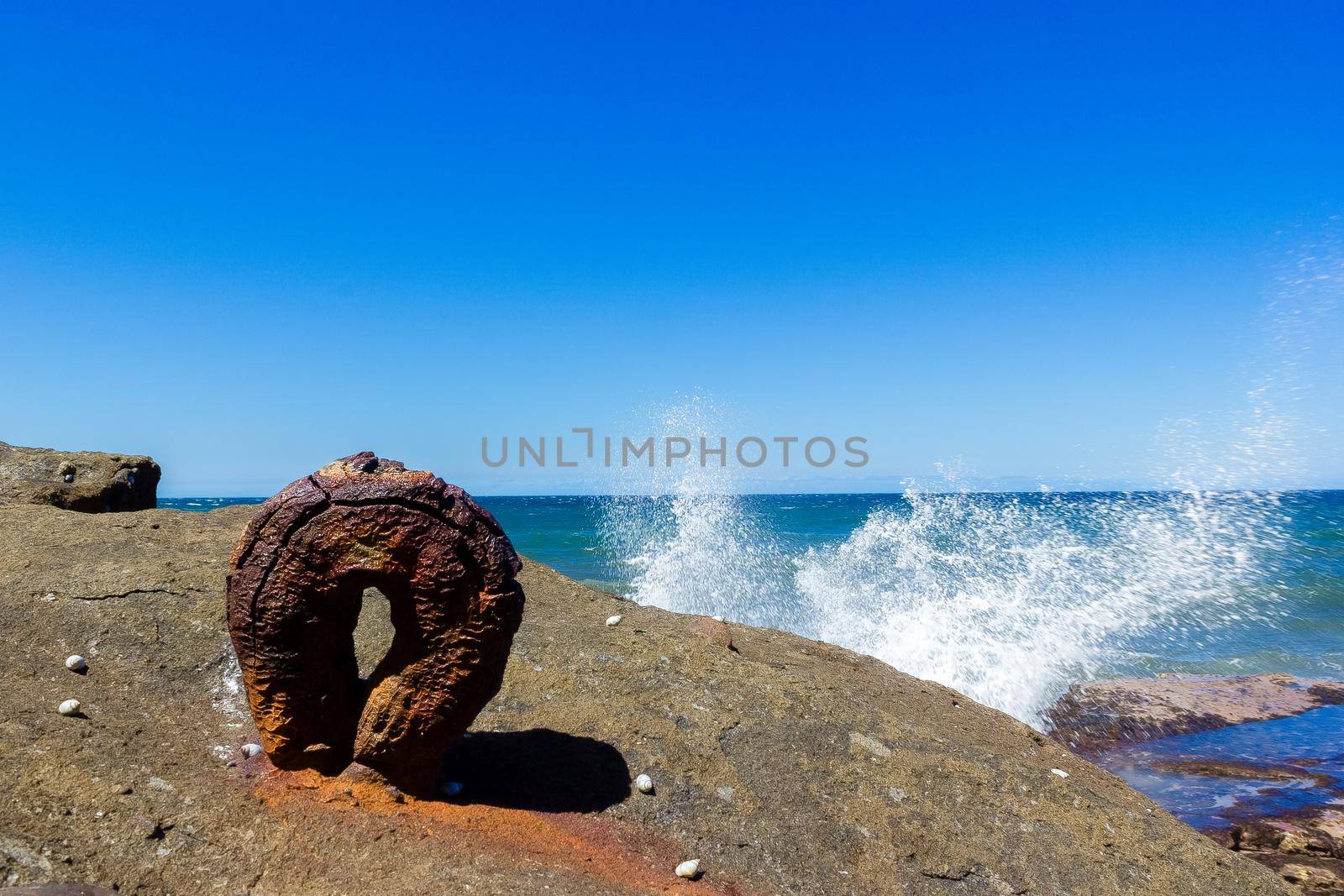 an old rusty round hook from the historic Sea Clliff Bridge with waves in the background, along the Grand Pacific Drive, Australia