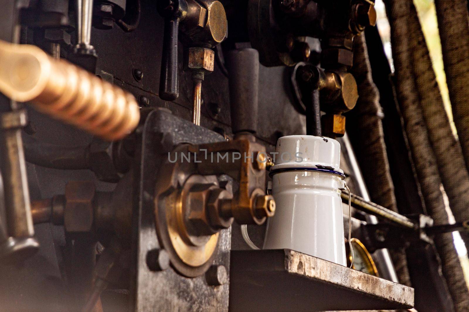 An old white enamel jug inside an old steam locomotive surrounded by metal levers and nuts