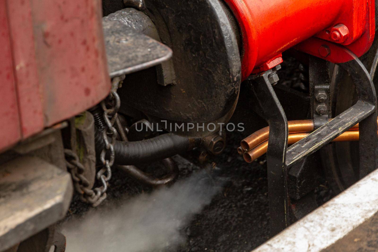 Two copper pipes expelling a jet of steam from an old train