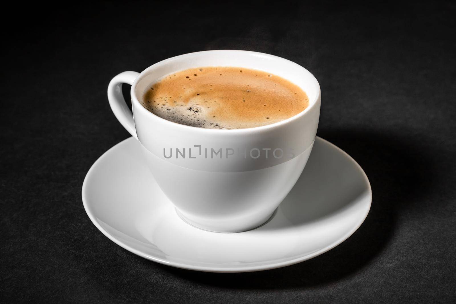 White cup of fresh black coffee on a dark background close-up