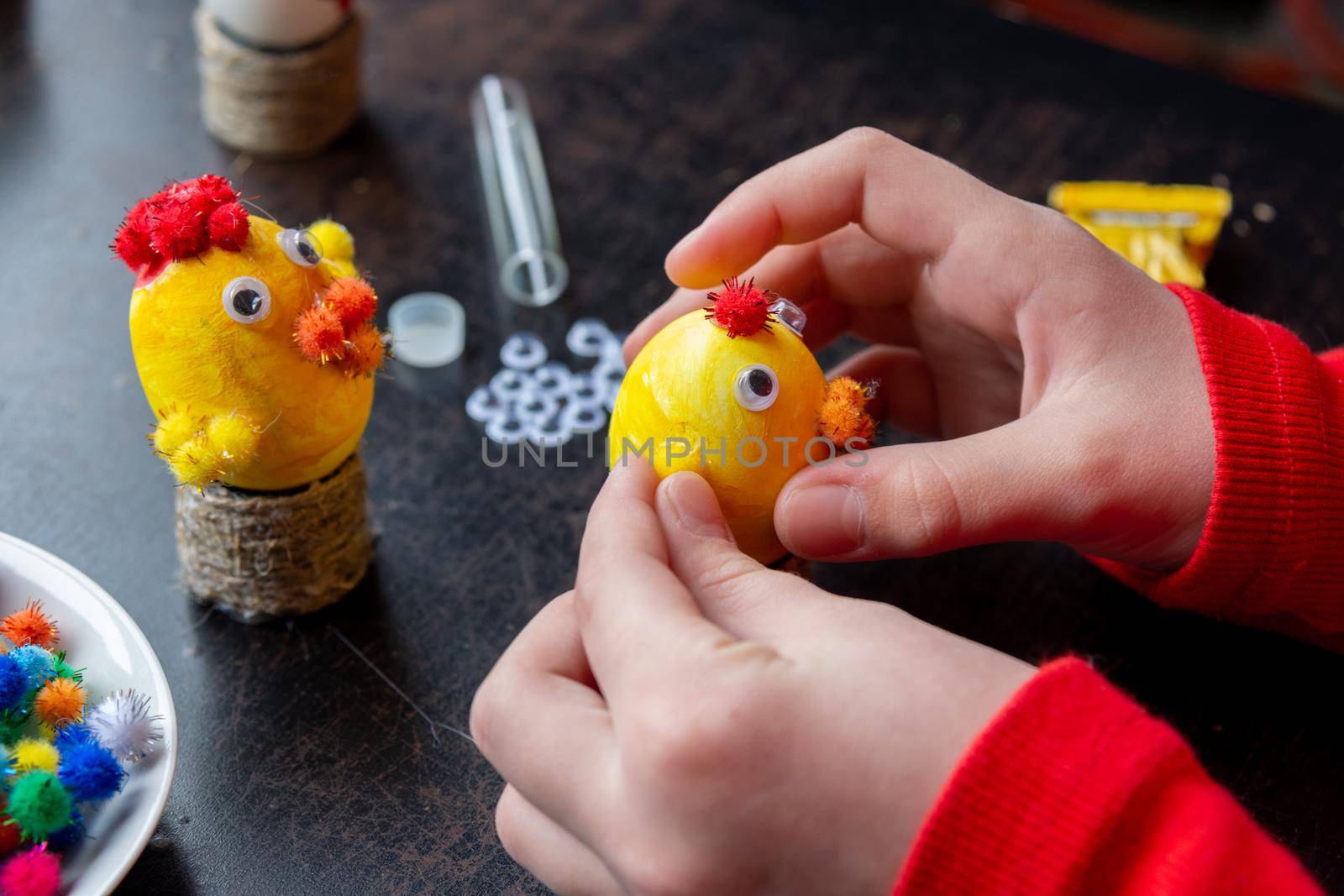 Children's hands make a craft from an egg for the Easter holiday