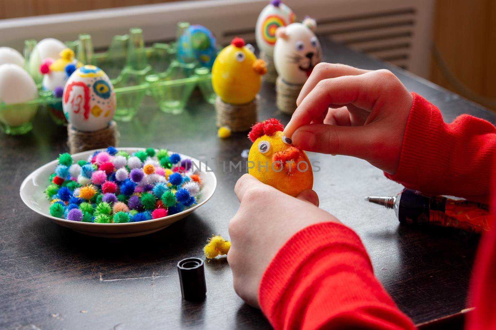 A child glues an eye to the shape of a chicken for Easter