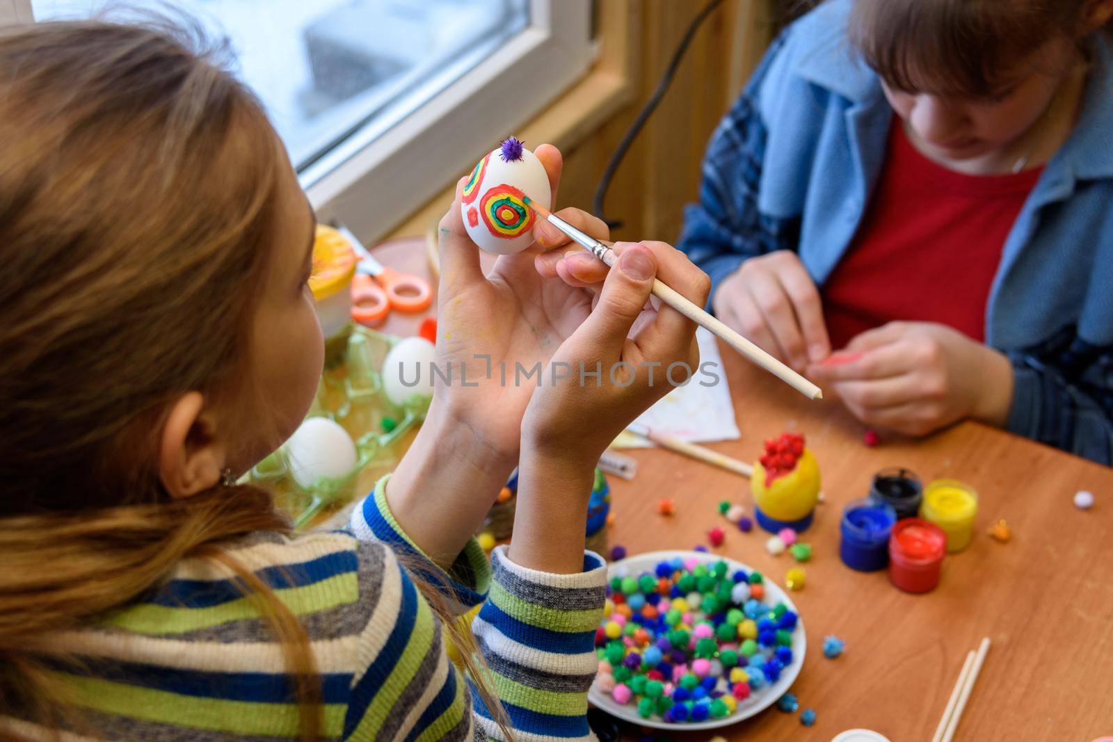Children at the table are painting Easter eggs for the holiday
