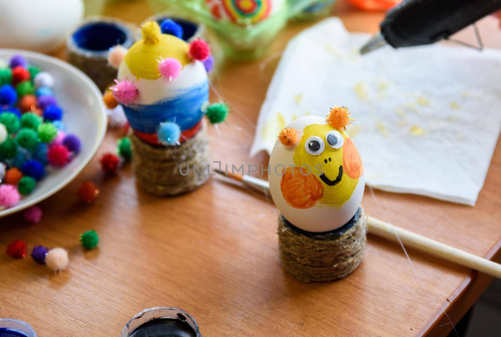 Painted easter egg with glued eyes stands on the table