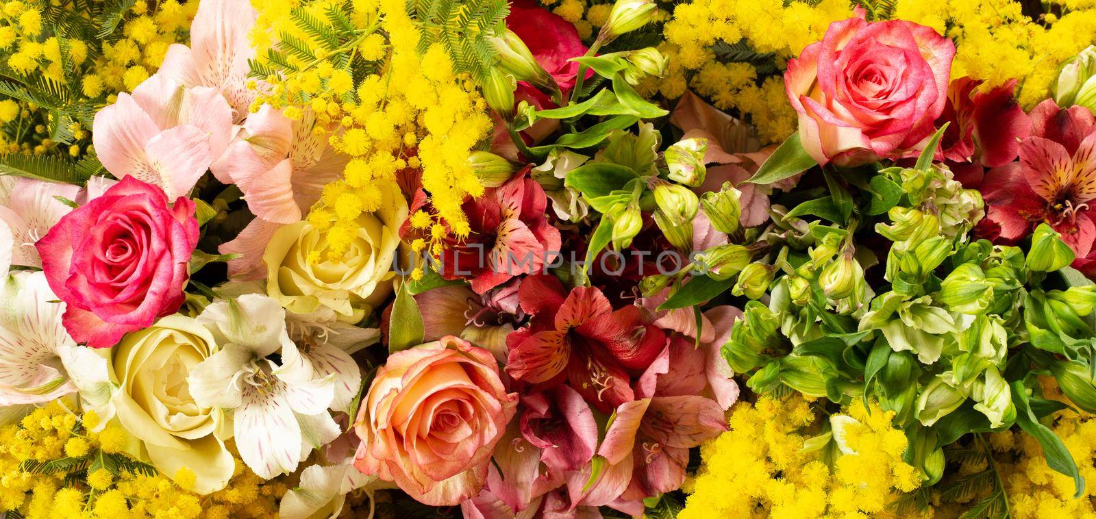 Flowers border composition in bright yellow red colours. Alstroemeria, roses, mimosa flowers. Flat lay top view, copy space