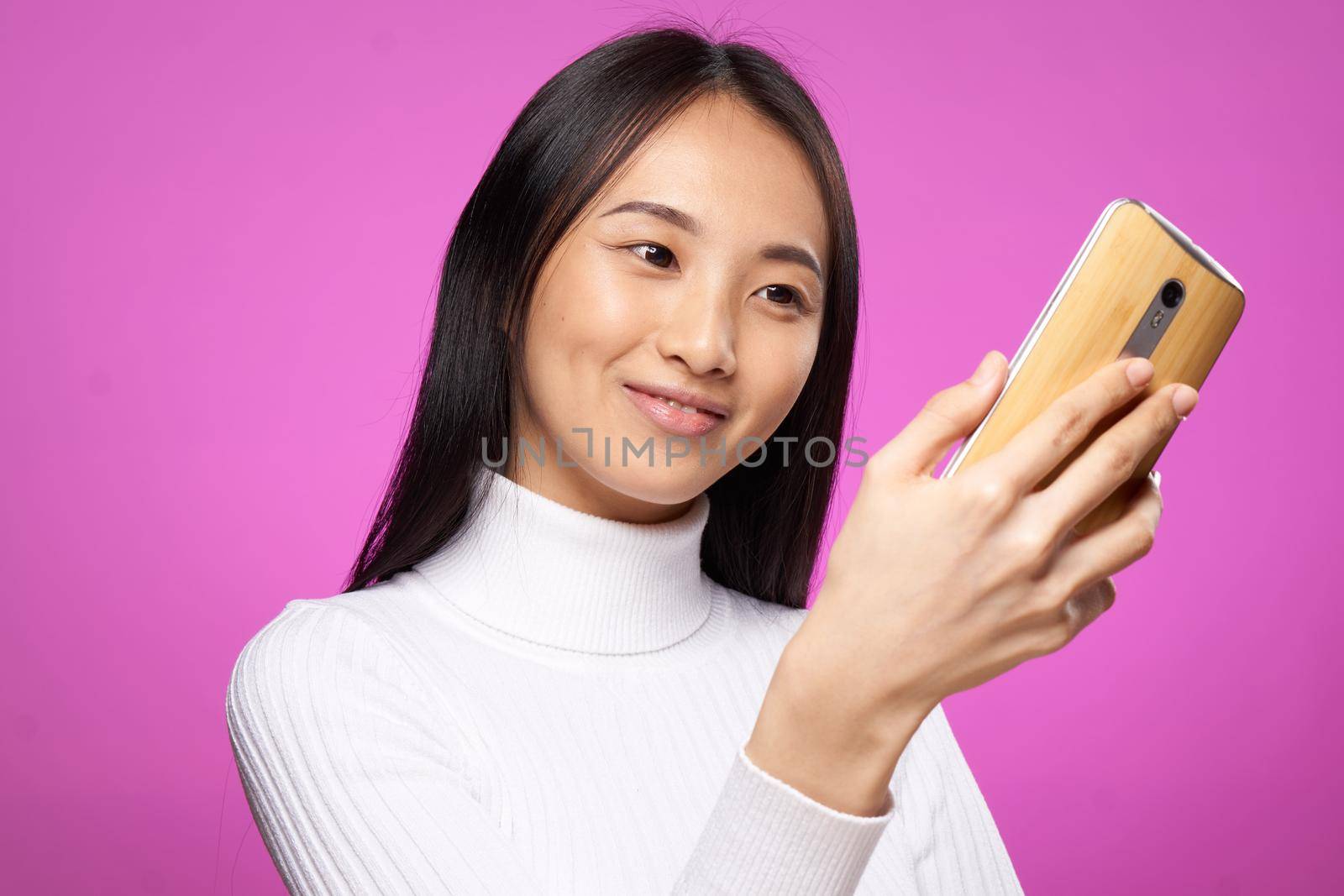 pretty woman with phone in hands white sweater technology communication pink background by SHOTPRIME