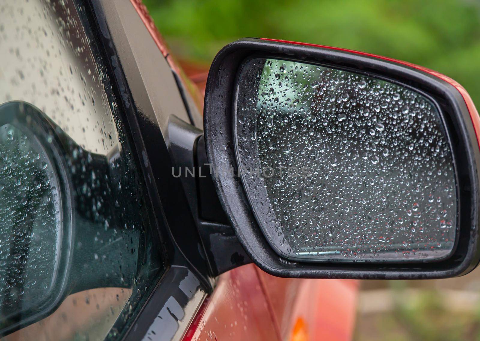 Closeup of car side rear view mirror with rain drops