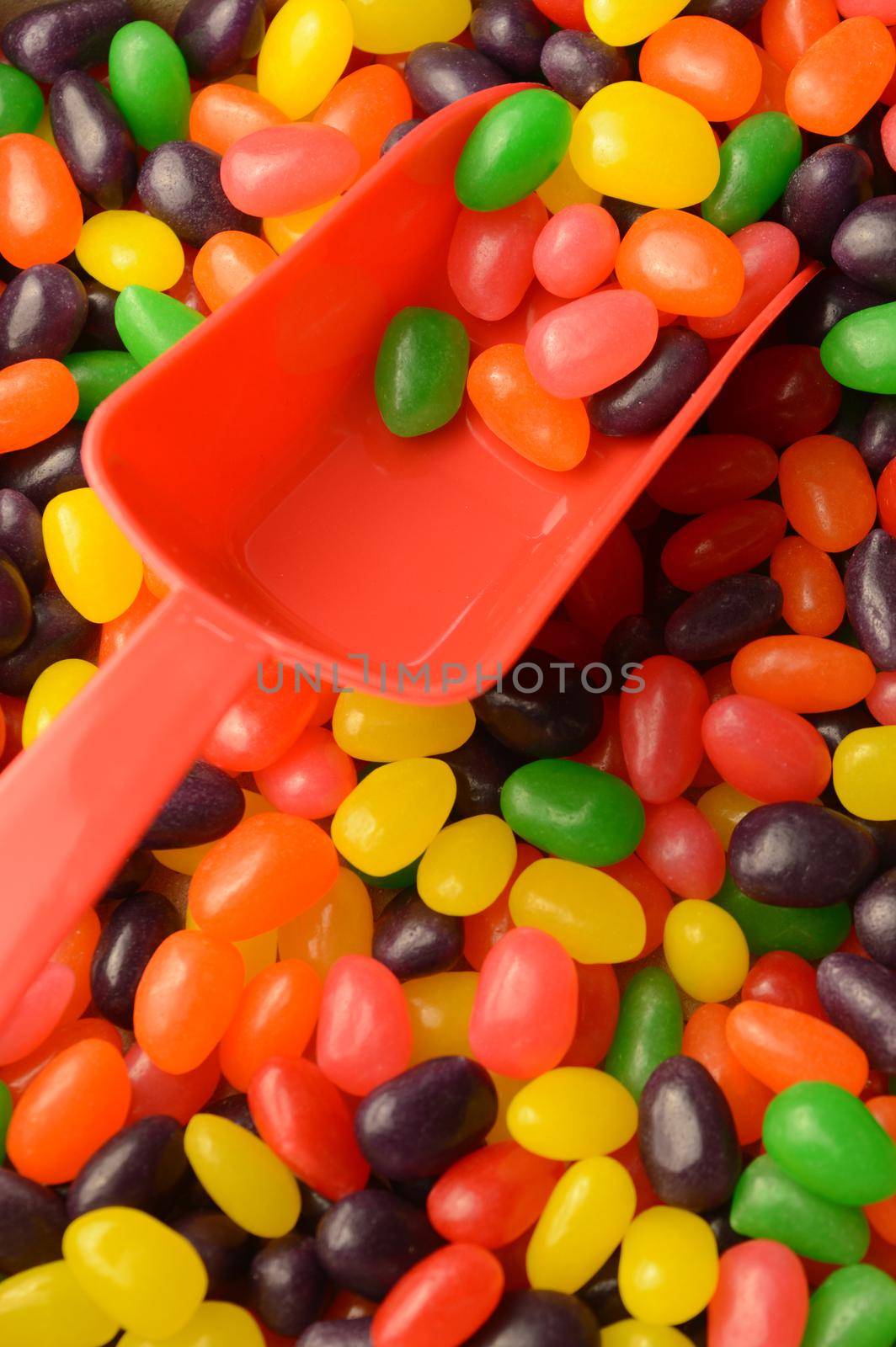A closeup view of a red scoop in an abundant supply of jelly bean candy.