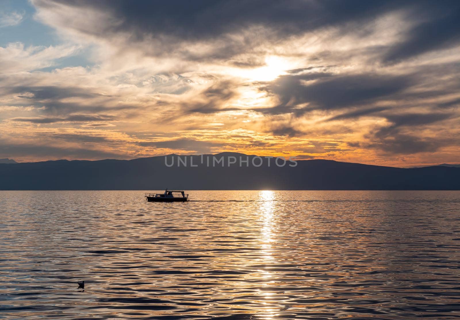 small tourist boat sails on a lake at sunset