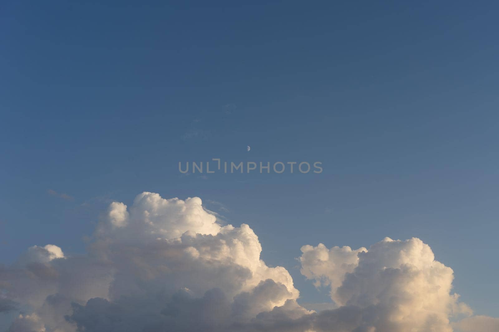 Natural background with clouds and a moon on the background of blue sky in clear weather