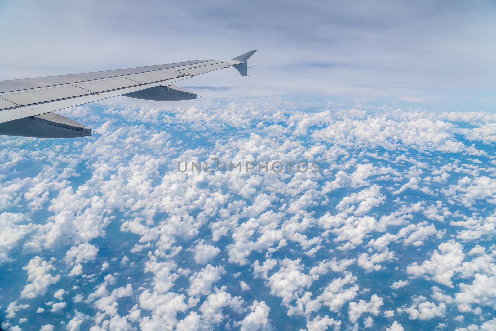 Aerial view above clouds from airplane window with blue sky.  Tropical climate in Thailand.