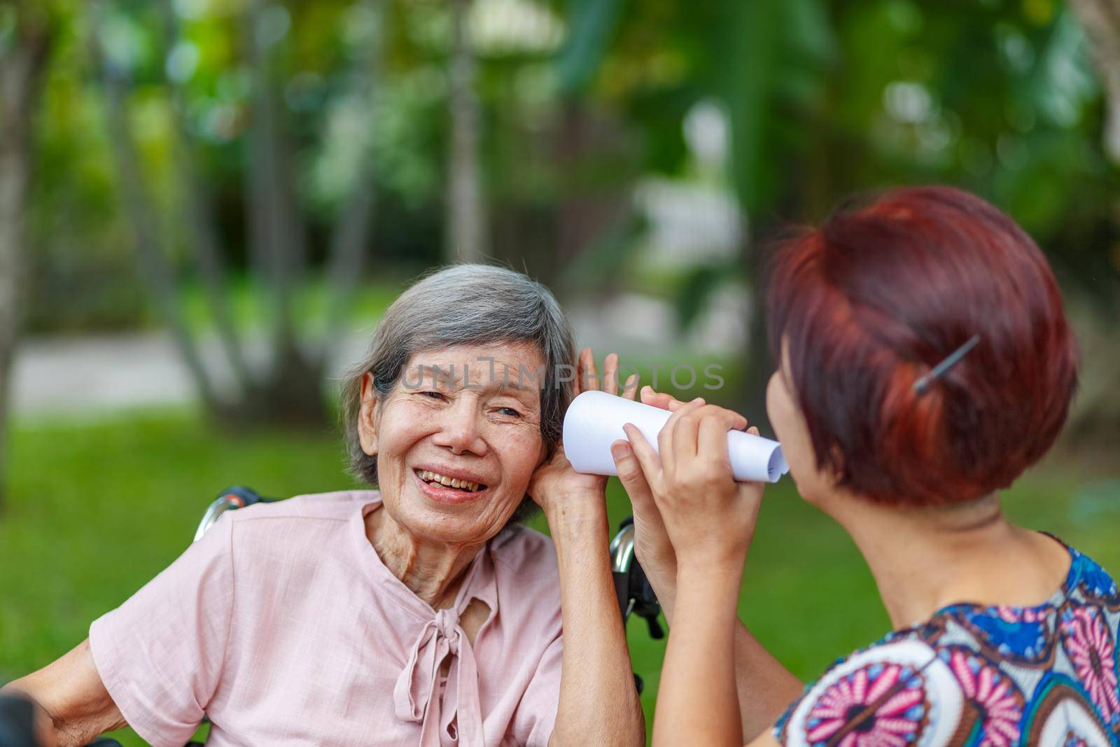Daughter talking to hearing impaired elderly woman , using paper tube by toa55