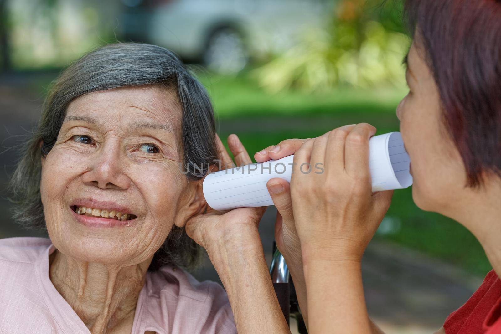 Daughter talking to hearing impaired elderly woman , using paper tube by toa55