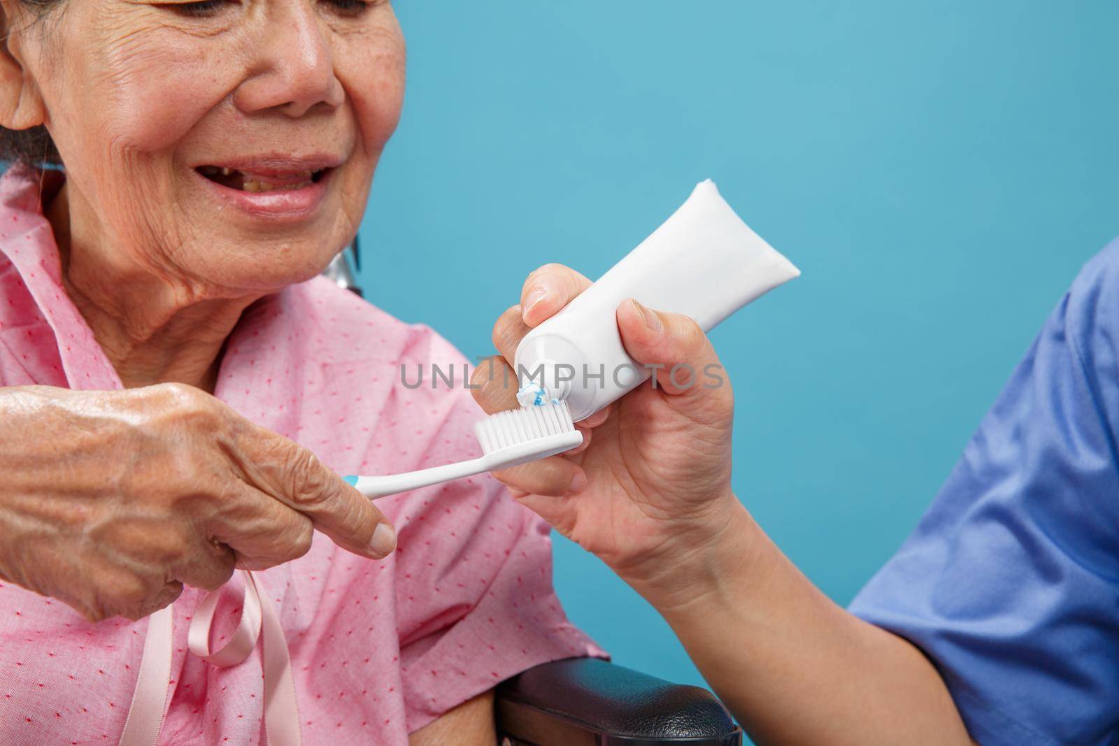 Caregiver take care asian elderly woman while using toothbrush.