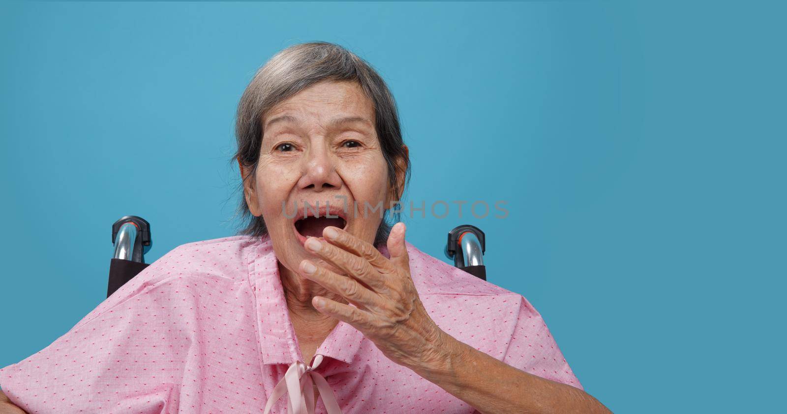 Elderly woman yawning on wheelchair
