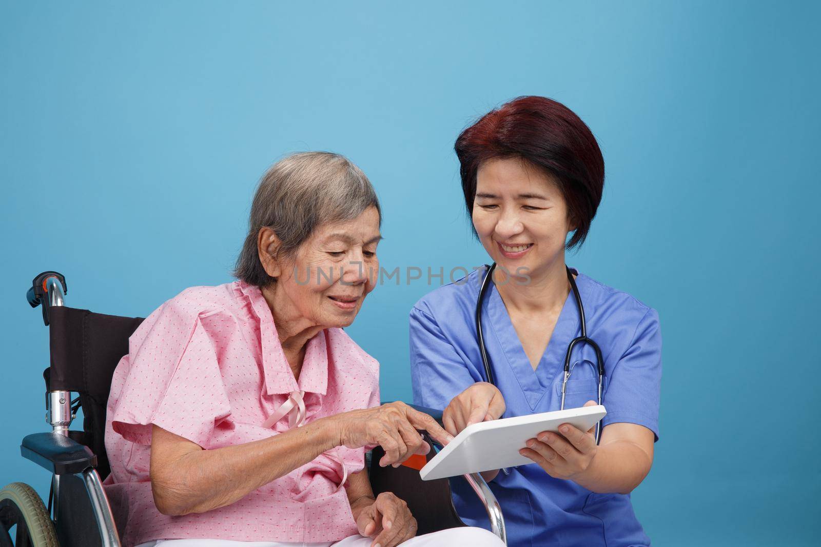Asian nurse talking with elderly female patient on wheelchair by toa55