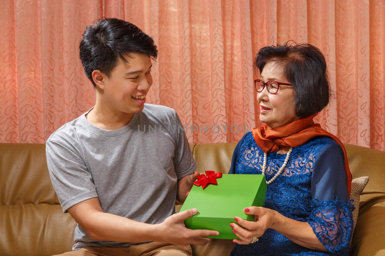 Adult son gives a present to mother on the mothers day by toa55