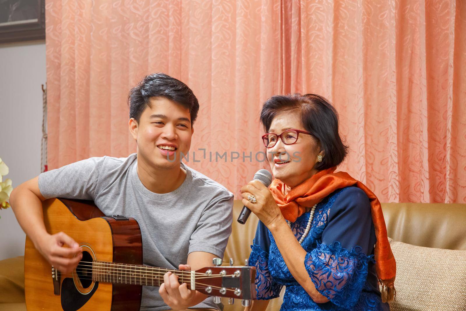 Adult son and senior mom sing a song while relaxed sitting on couch