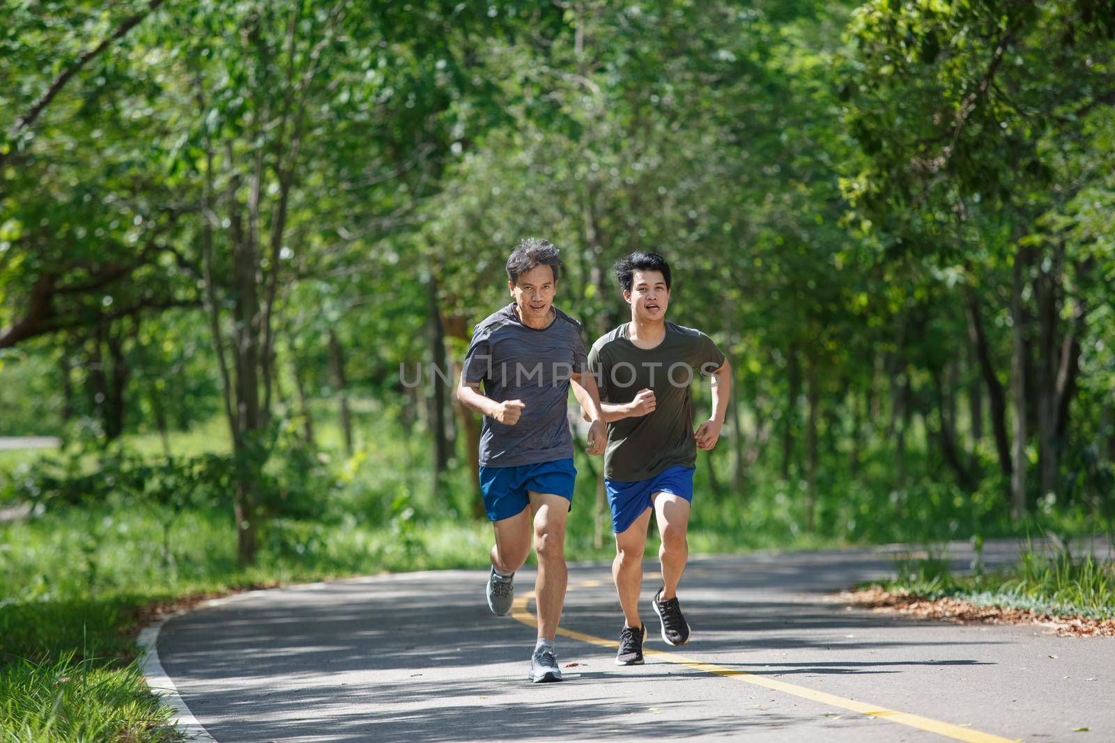 Father and adult son jogging on the park path