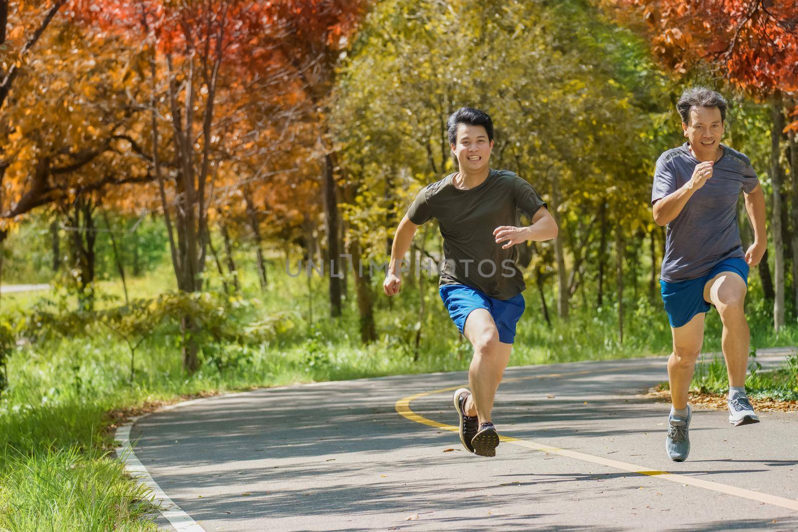 Father and adult son running together on the park path