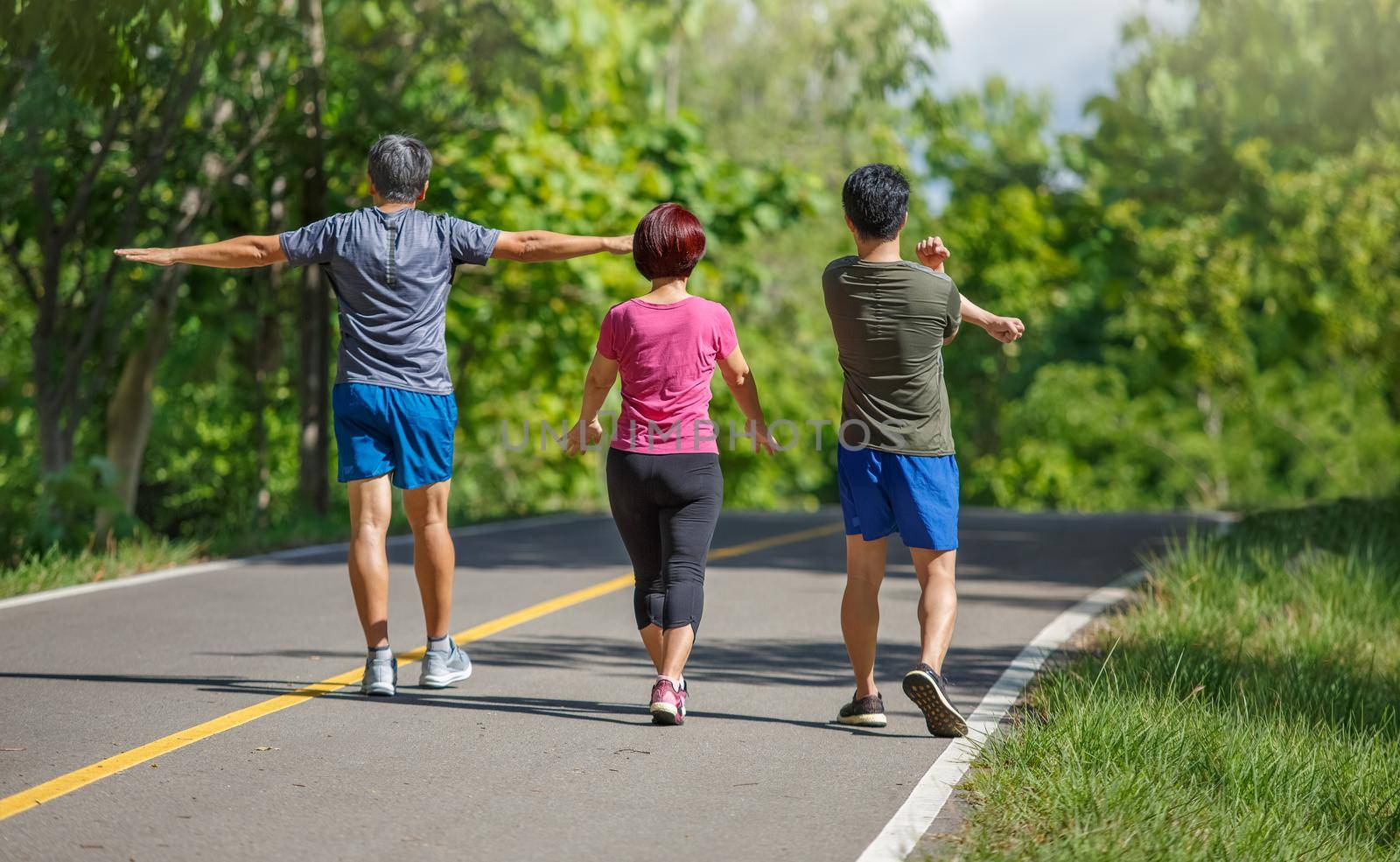 Father mother and adult son exercise in the park