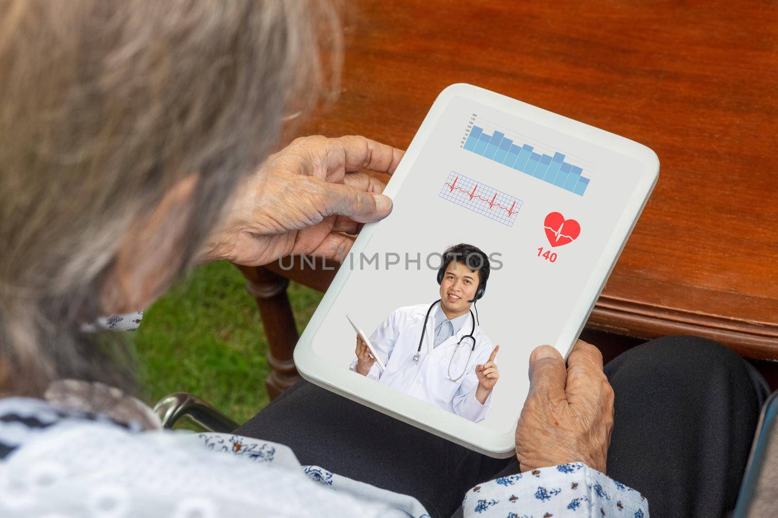 Elderly woman sit at home having online consultation with doctor on tablet computer.