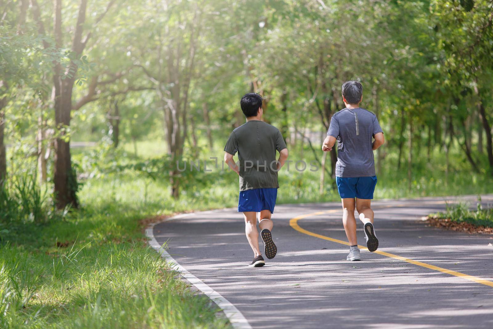 Father and adult son jogging on the park path by toa55