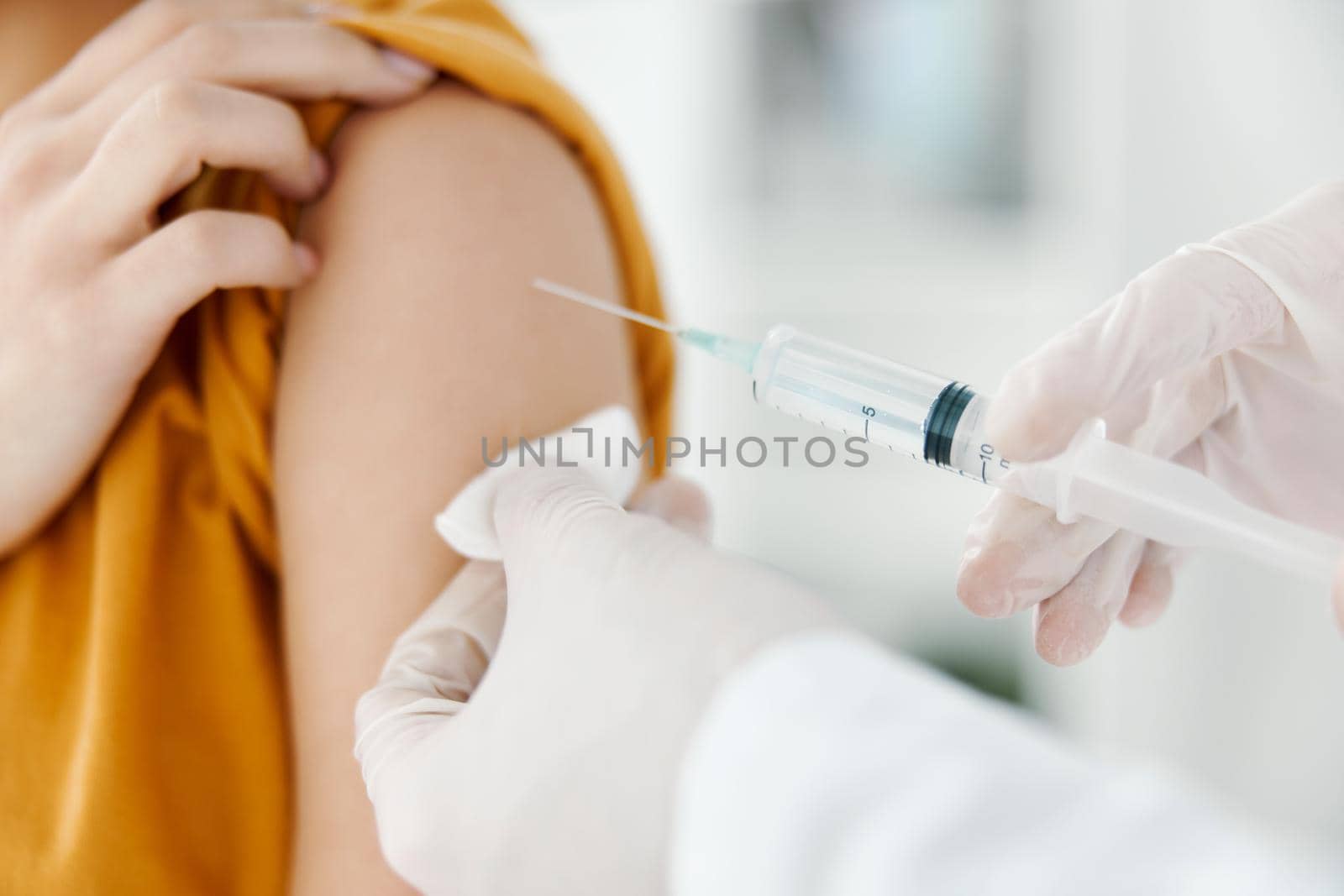 doctor injecting vaccine into shoulder of patient wearing medical mask in hospital epidemic. High quality photo