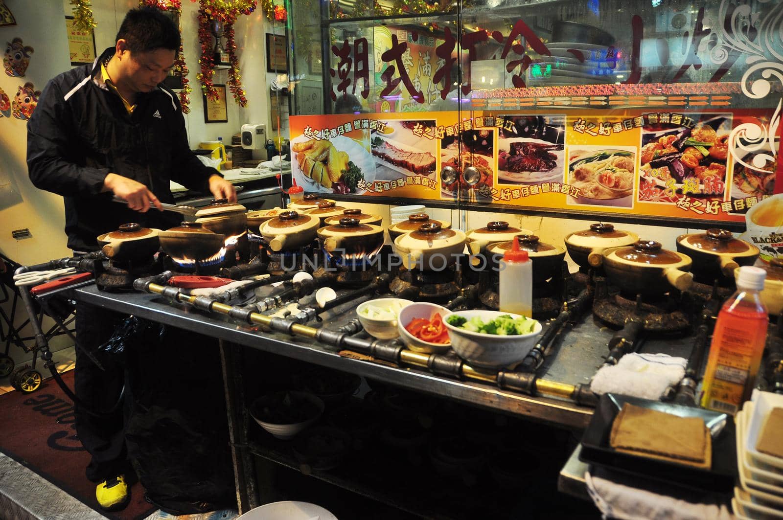 HONG KONG - 23th FEBRUARY, 2015 Asian man cooking street food for sale at stand with pots and cookware, Hong Kong. Ethnic man at stall making street food
