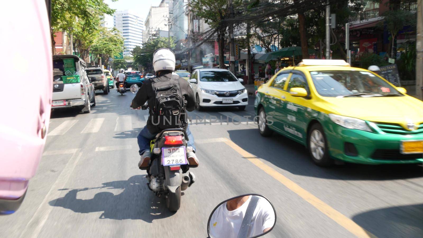 BANGKOK, THAILAND - 18 DECEMBER, 2018: Fast movement through traffic jam in an overpopulated asian city. View from the passenger perspective of a moto taxi. public transport.