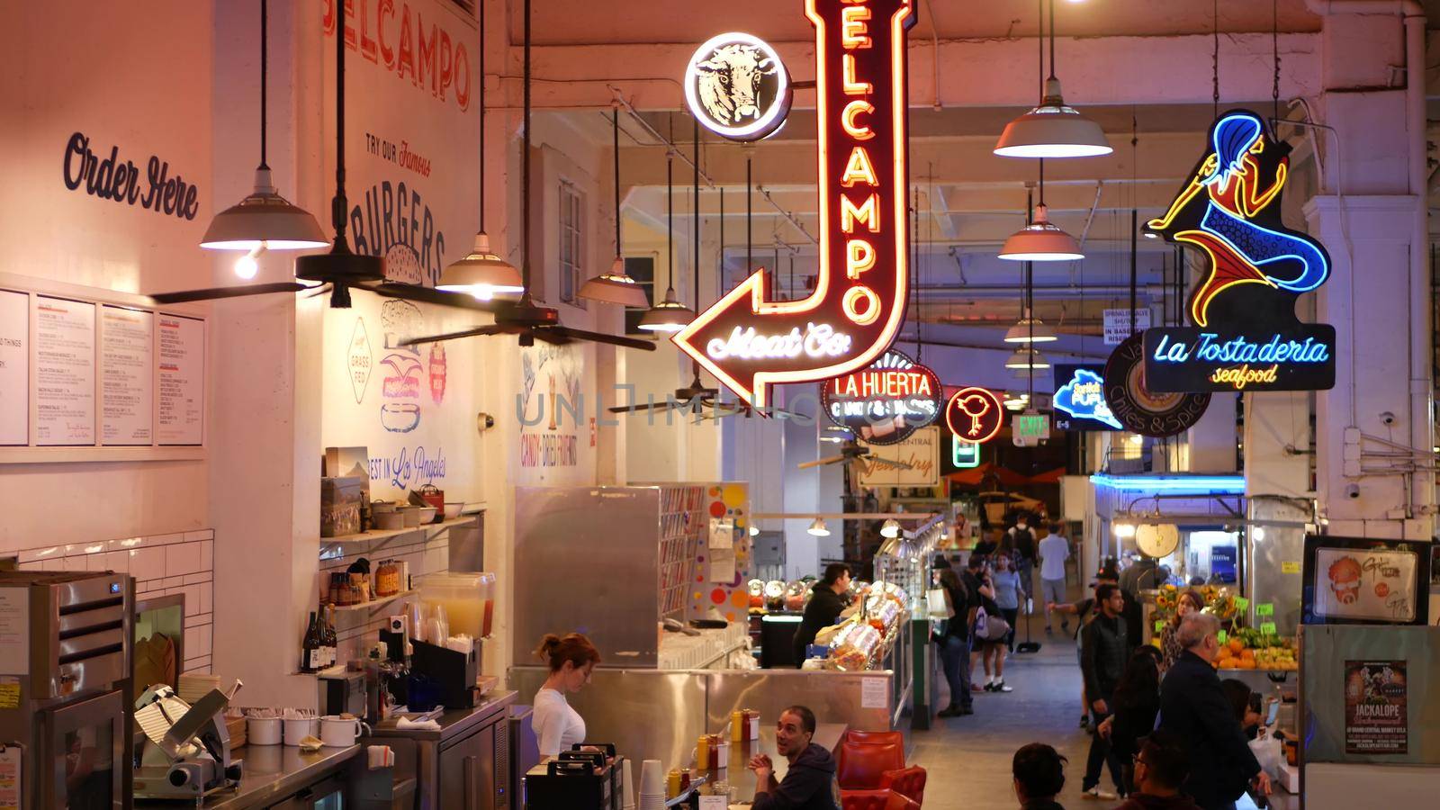 LOS ANGELES, CALIFORNIA, USA - 27 OCT 2019: Grand central market street lunch shops with diversity of glowing retro neon signs. Multiracial people on foodcourt. Citizens dining with fast food in LA.