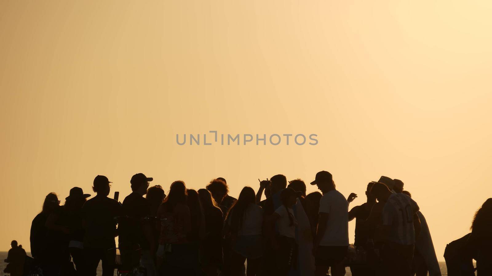 LOS ANGELES CA USA - 16 NOV 2019: California, happy young multiracial friends having fun and hanging out. Group of multiethnic people dancing on party in sunset light. Venice beach summertime leisure.