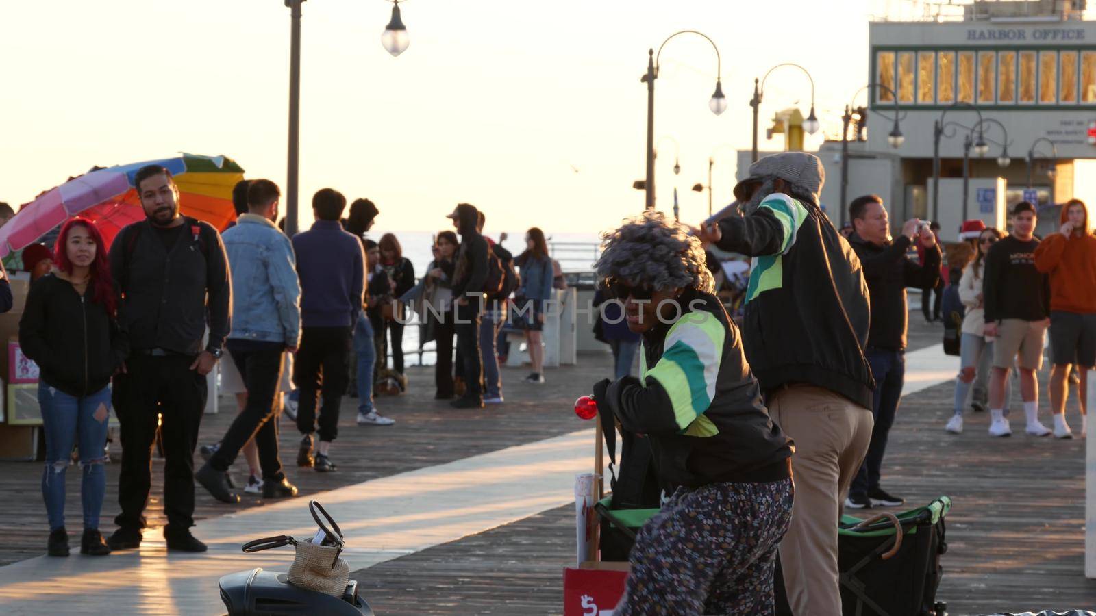 SANTA MONICA, LOS ANGELES CA USA - 19 DEC 2019: African american street performer dancing on boardwalk. Two black ethnicity positive dancers having fun. Pier promenade, smiling multiethnic pedestrians