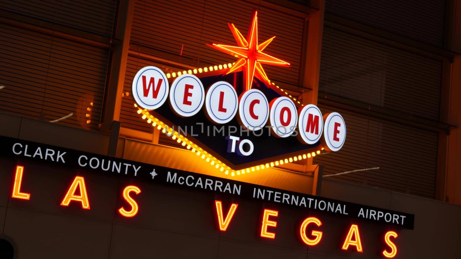 LAS VEGAS, NEVADA USA - 9 MAR 2020: Welcome to fabulous Sin City illuminated retro neon sign inside McCarran airport. Iconic greeting vintage styled signboard glowing. Gambling casino resort symbol by DogoraSun
