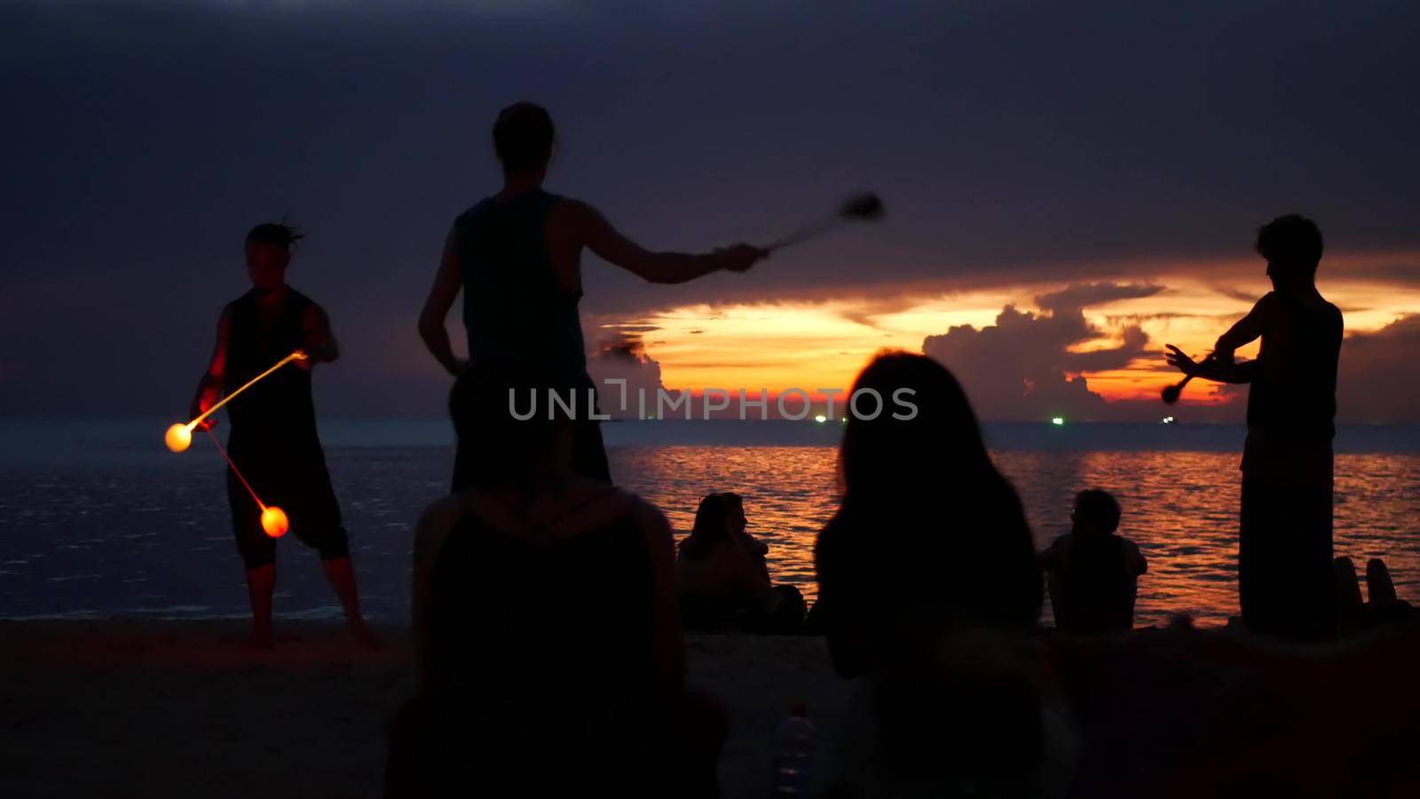 PHANGAN, THAILAND - 23 MARCH 2019 Zen Beach. Silhouettes of performers on beach during sunset. Silhouettes of young anonymous entertainers rehearsing on sandy beach against calm sea and sundown sky