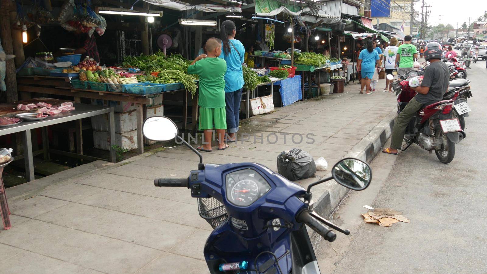KOH SAMUI ISLAND, THAILAND - 10 JULY 2019: Food market for locals. Lively ranks with groceries. Typical daily life on the street in Asia. People go shopping for fruits vegetables, seafood and meat