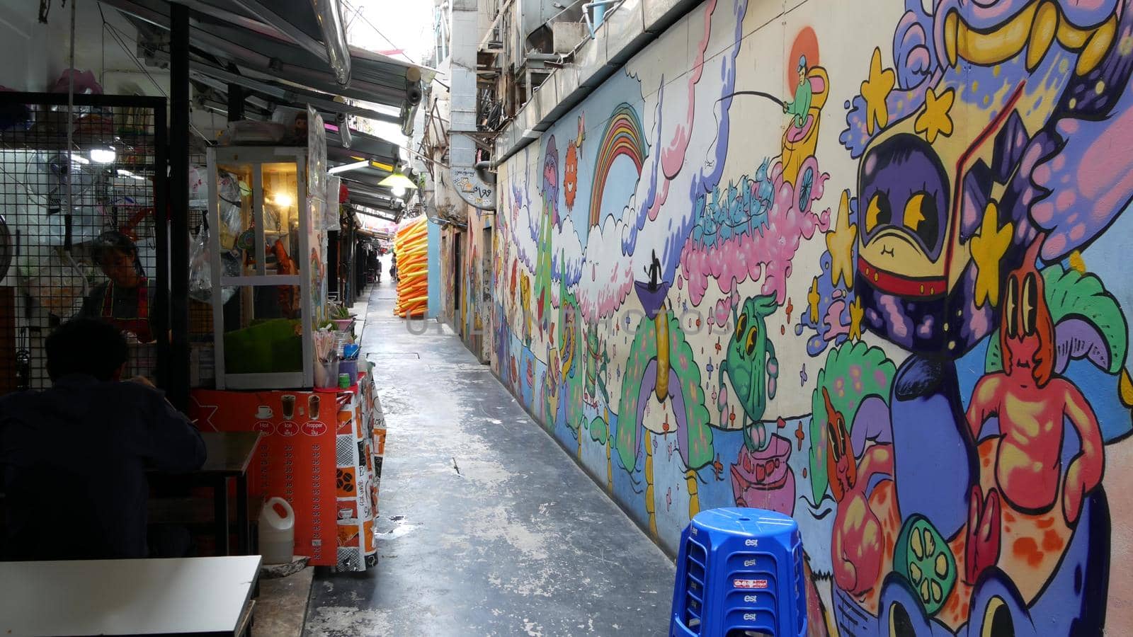 BANGKOK, THAILAND - 11 JULY, 2019: Food cart near graffiti wall on street. Food cart located near colorful graffiti wall on market on narrow street. Local traditional streetfood.