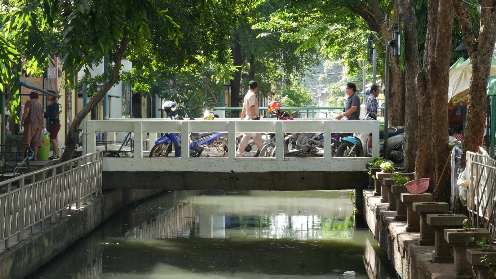 BANGKOK, THAILAND - 11 JULY, 2019: Street city life near river canal in siam. Traditional khlong with bridge near local market. Thai people on the riverside. Classic water way in Krungtep. by DogoraSun