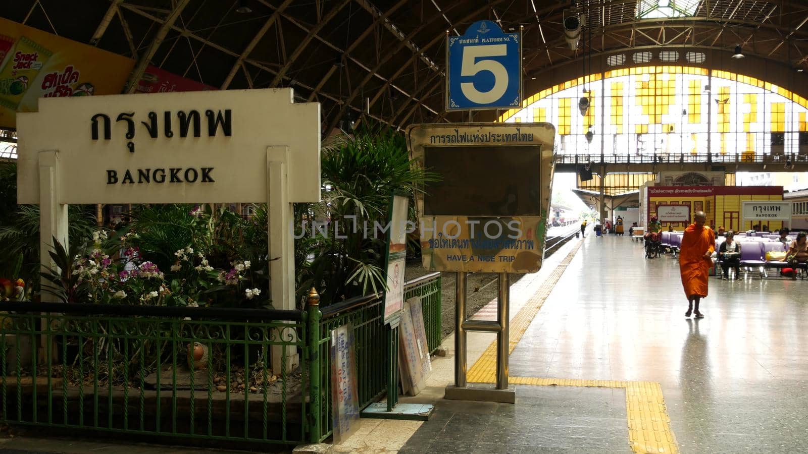 BANGKOK, THAILAND - 11 JULY, 2019: Hua Lamphong railroad station, state railway transport infrastructure SRT. Buddhist holy Monk in traditional orange robe. Monks yellow religious clothes among people by DogoraSun