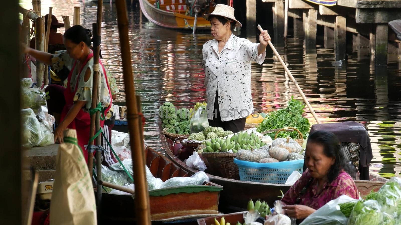 BANGKOK, THAILAND - 13 JULY 2019: Lat Mayom floating market. Traditional classic khlong river canal, local women farmers, long-tail boats with fruits and vegetables. Iconic asian street food selling. by DogoraSun